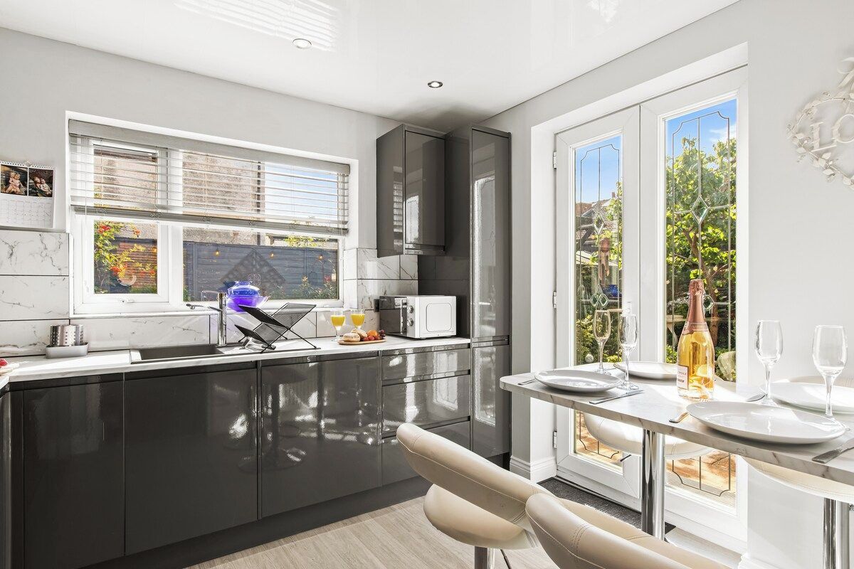 A modern kitchen with a large window, a dining area with a table set for two, and a view of the outdoors.