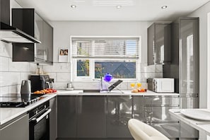 Une cuisine moderne équipée d’un four encastré, d’un four à micro-ondes et d’un évier.