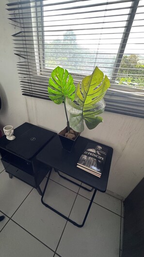A small table with a potted plant, a mug, and a book.