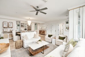 Ein geräumiges Wohnzimmer mit einem weißen Sofa, einem Couchtisch und einem Deckenventilator.