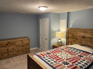 A bedroom with a wooden bed, a dresser, a nightstand with a lamp, and a door. - Spacious 4BR Townhome, Sleeps 8, Canal Fulton (Canal Fulton)