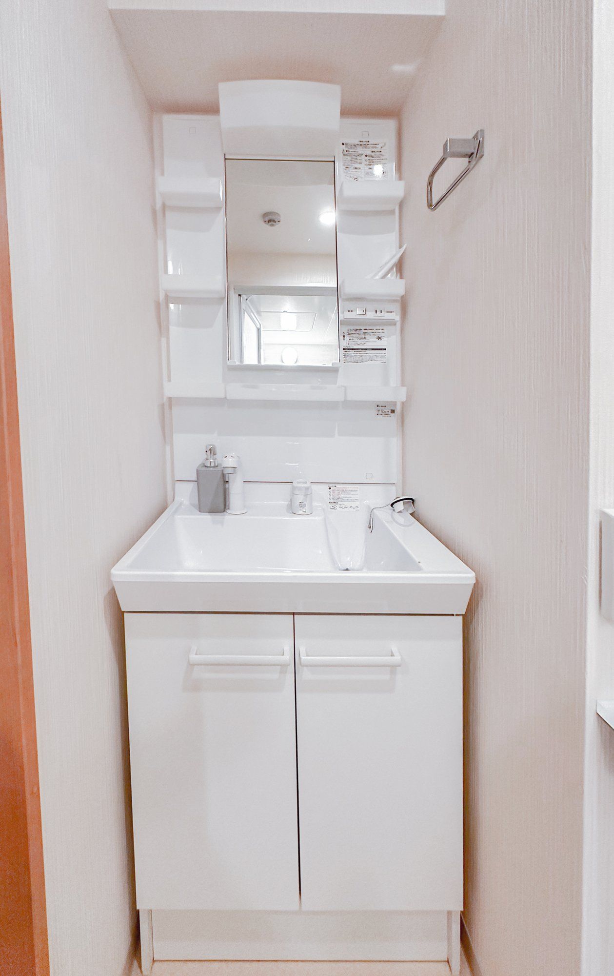 A white bathroom with a sink, mirror, and cabinets.