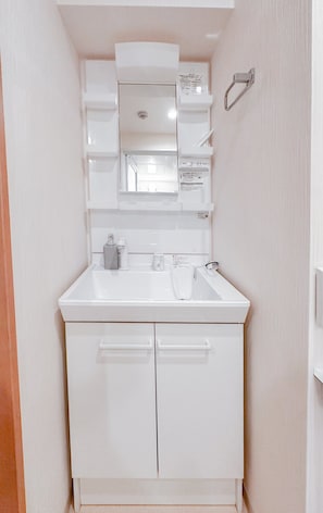 A white bathroom with a sink, mirror, and cabinets. - HANASTAY CHUO KOKAN 503 (Osaka)