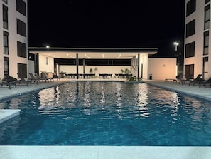A swimming pool with lounge chairs and a covered seating area.