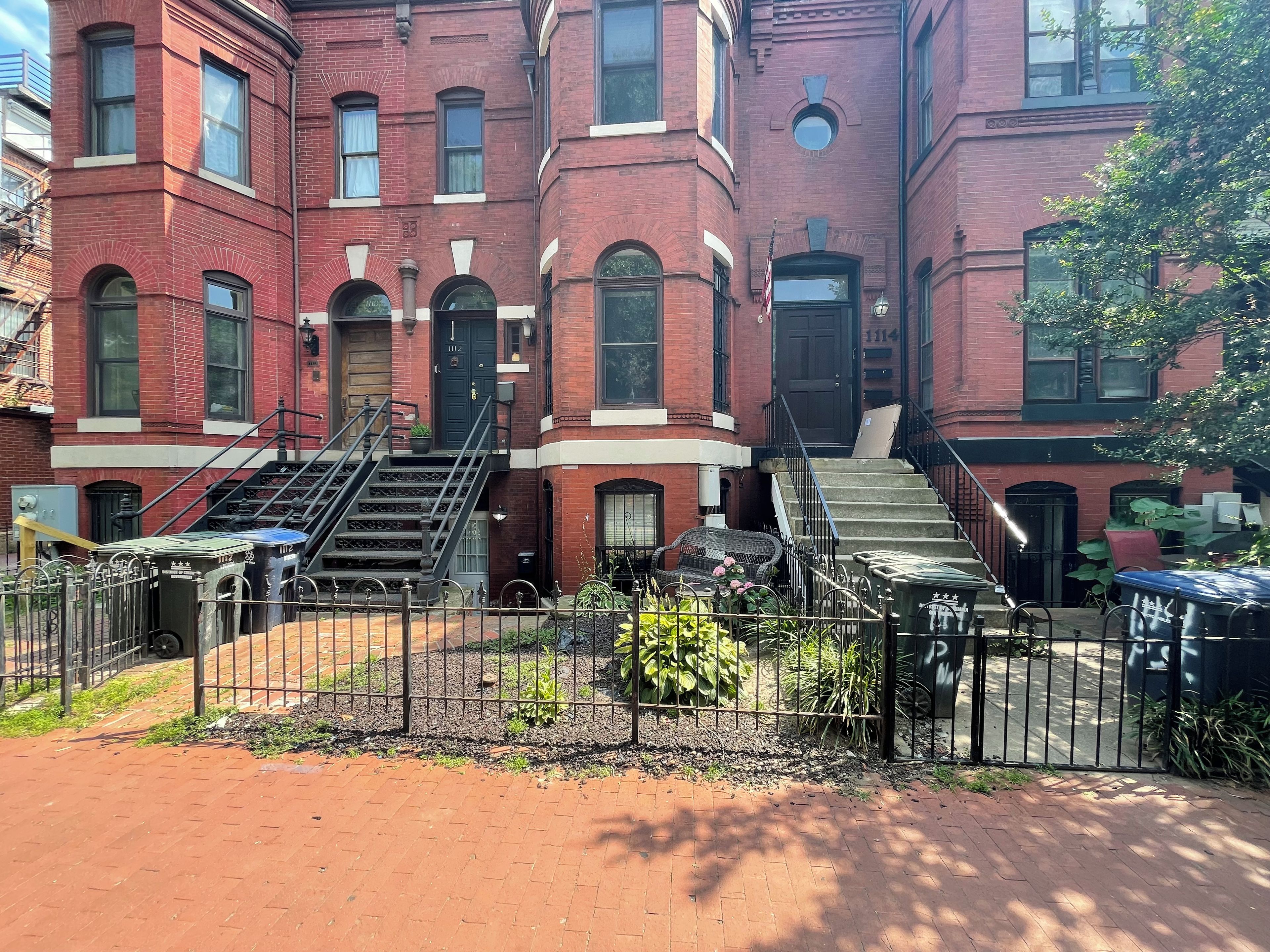 A red brick building with multiple windows and a set of stairs leading to the entrance.