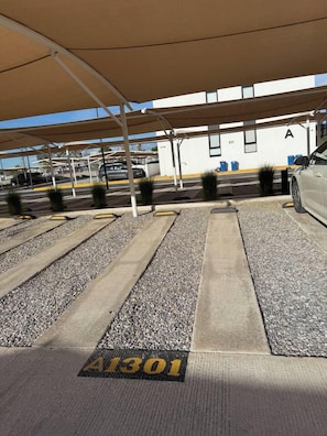 A parking area with marked spaces, a car, and a building with the letter 'A' on it. - Departamento de 1 recámara frente al Estadio TSM, alberca y gimnasio (Torreón)