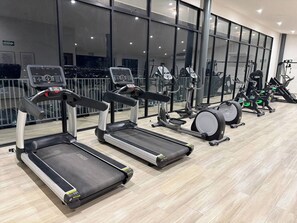Une salle de sport équipée de tapis de course, d’appareils elliptiques et de vélos d’appartement.