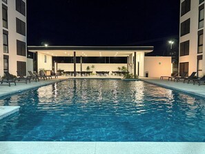 Une piscine avec des chaises longues et un espace salon abrité.