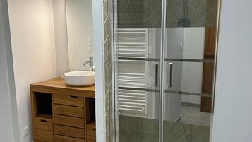Une salle de bain moderne avec une douche à parois de verre, un meuble-lavabo en bois et un miroir.