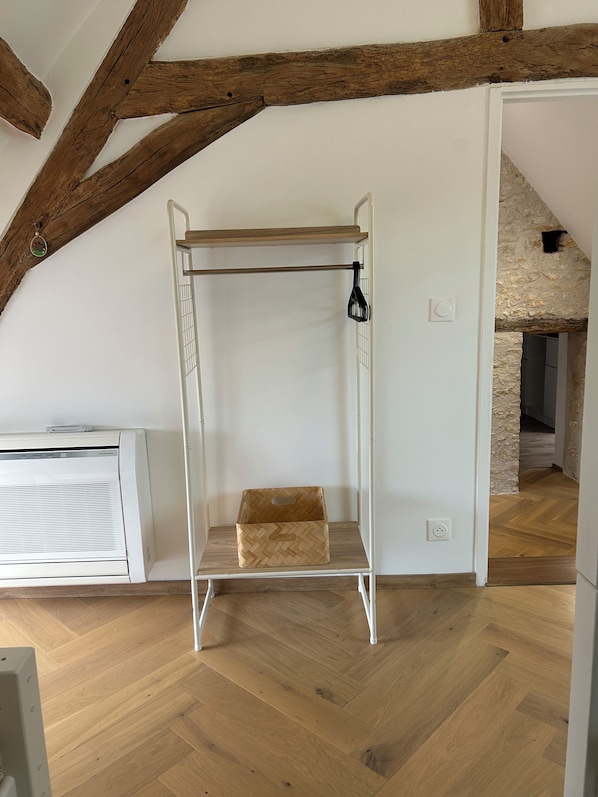 A room with a white metal bench, a white radiator, and a herringbone wooden floor.