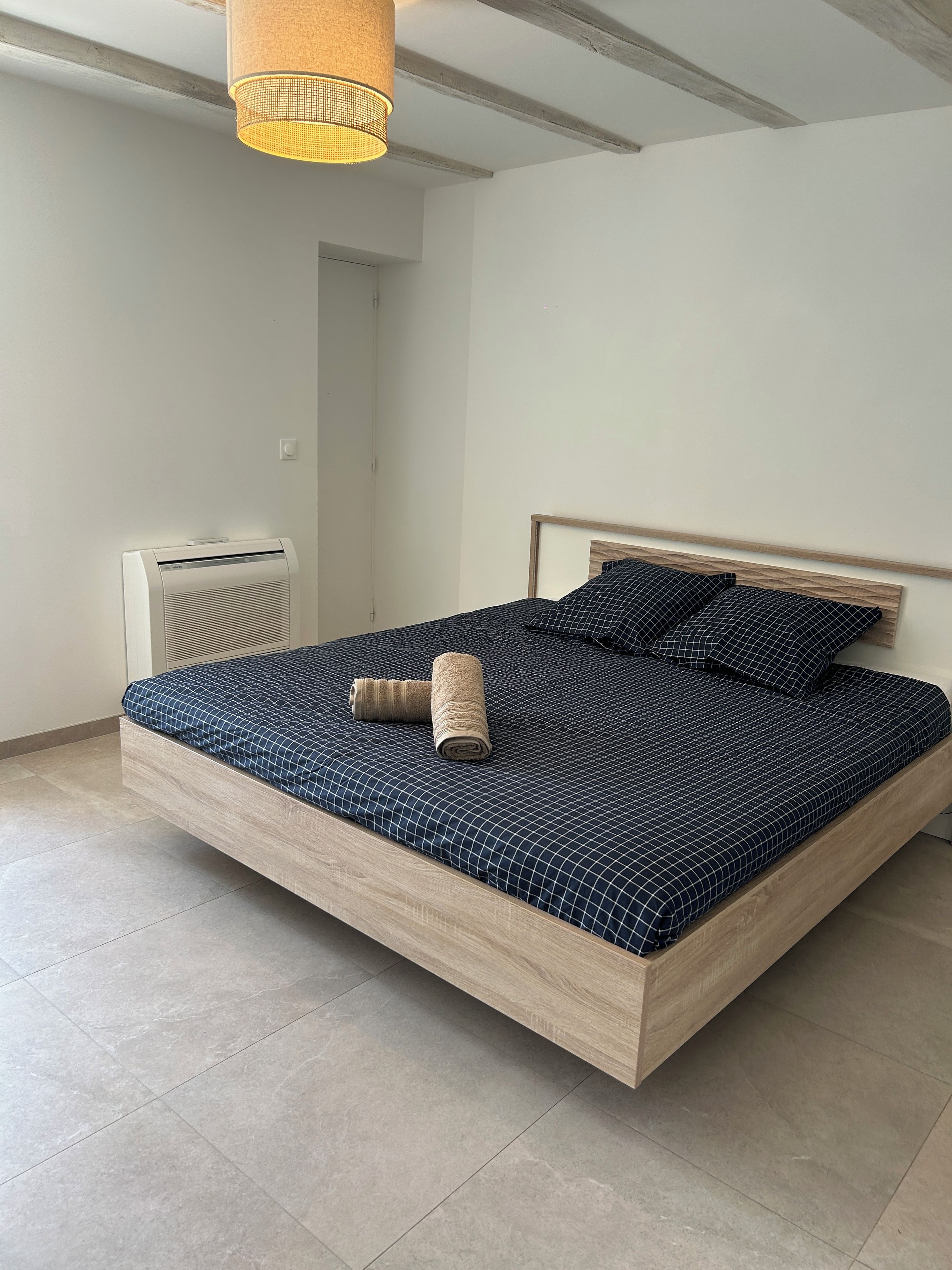 Un dormitorio con una cama grande, un calentador junto a la cama y una lámpara colgante.