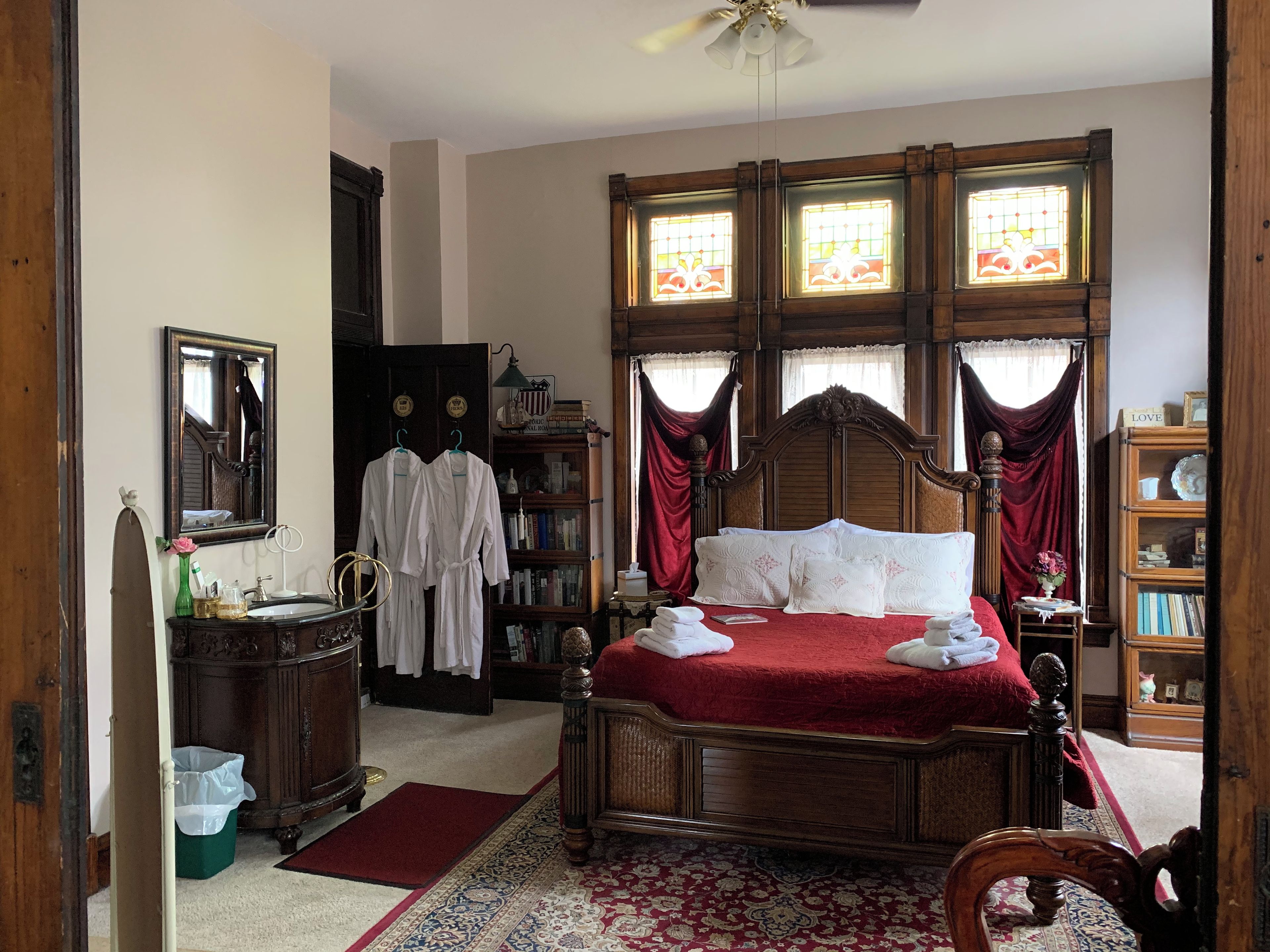 Een traditionele slaapkamer met een hemelbed, een houten garderobe en een boekenplank.