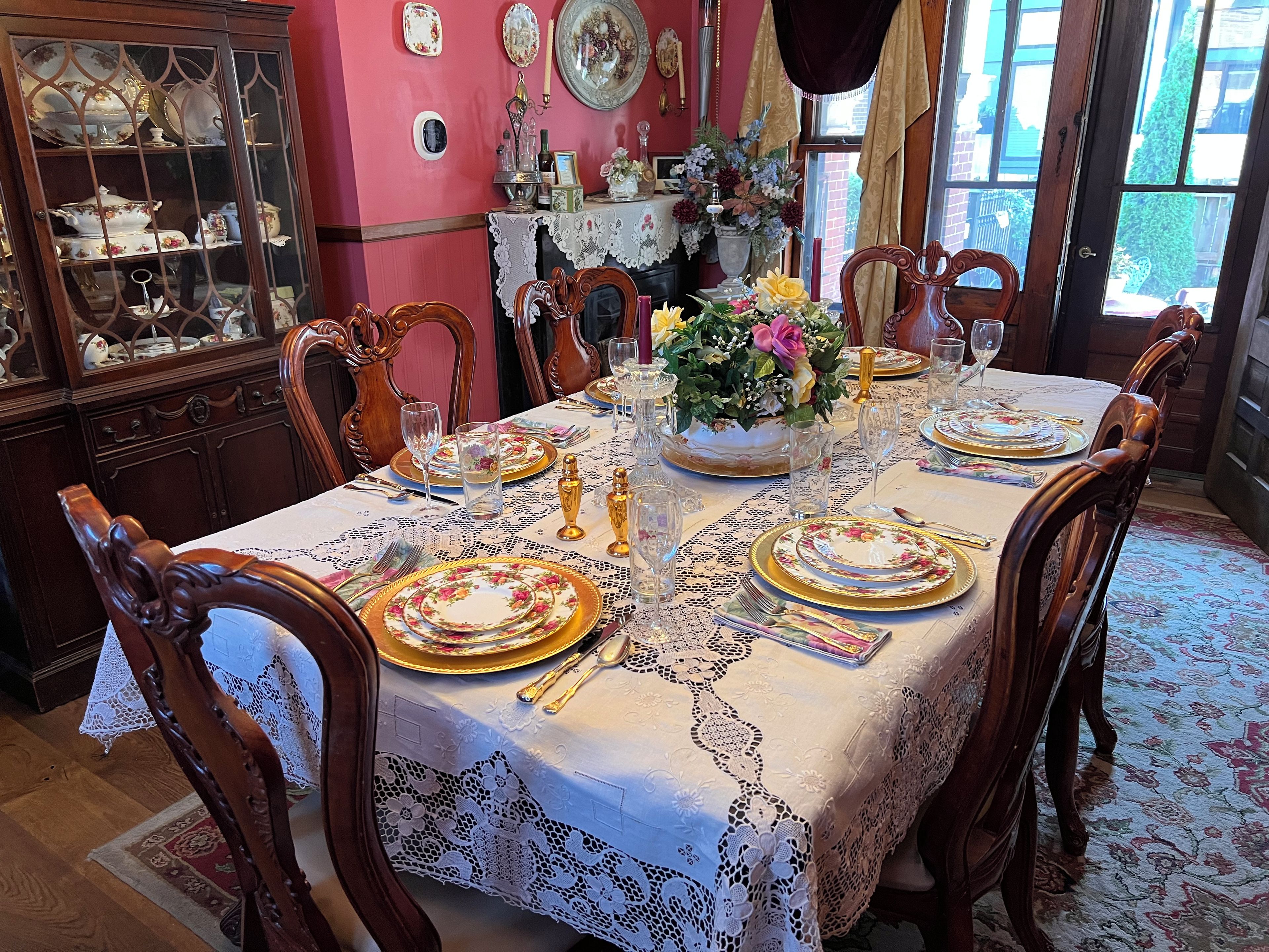 A dining room with a table set for six, surrounded by wooden chairs.
