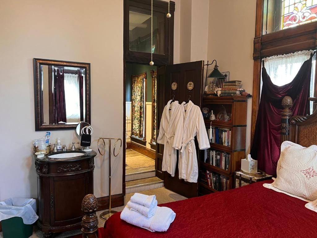 A hotel room with a bed, a vanity with a mirror, a bookshelf, and a door leading to a hallway.