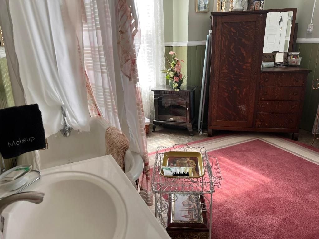 A bathroom with a white sink, a mirror, a vanity, a wooden cabinet, and a red carpet.