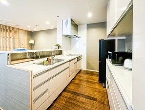 A modern kitchen with a wooden floor, a built-in sink, and a black refrigerator. - HANASTAY NISHIKI NIPPONBASHI (Osaka)