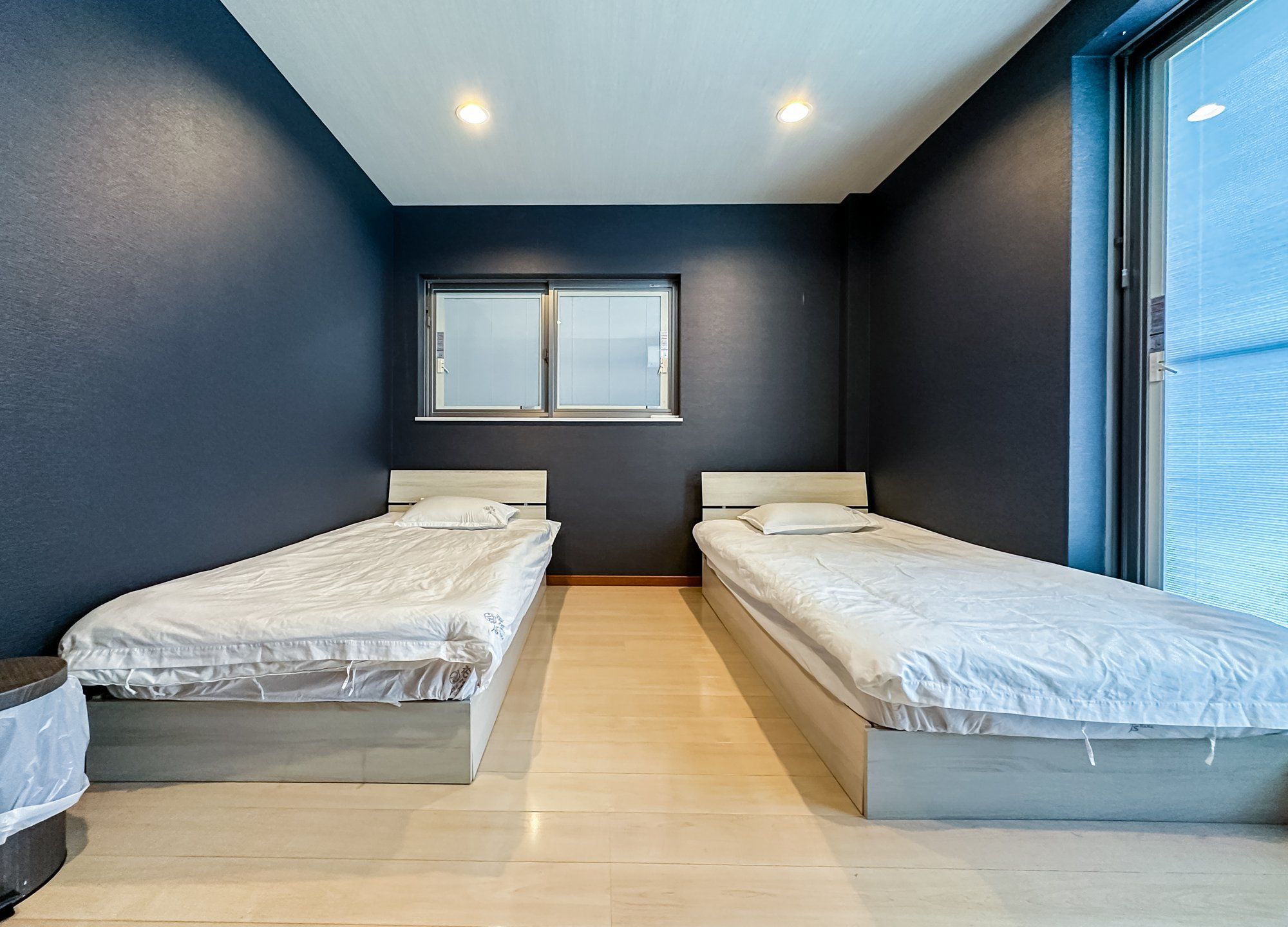 A bedroom with two single beds, a window, and a ceiling light.