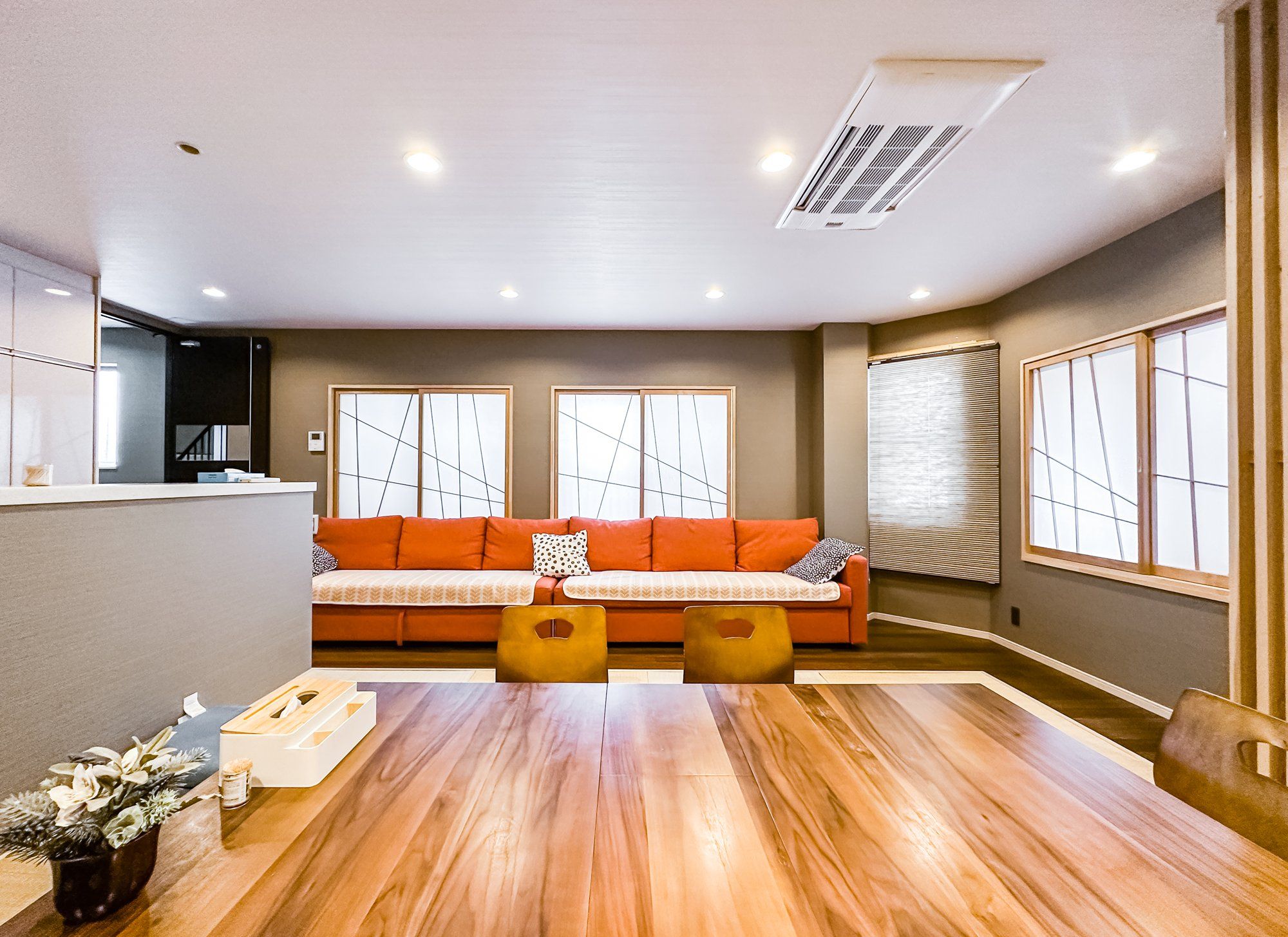 A modern living room with a sofa, a dining table, and a kitchen area.