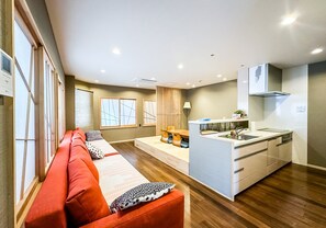A modern living room with a sofa, a kitchen area with a sink, and a dining table. - HANASTAY NISHIKI NIPPONBASHI (Osaka)