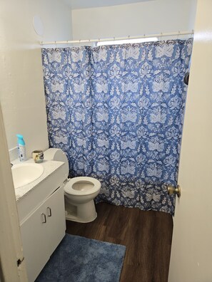 Ein Badezimmer mit Toilette, Waschbecken und einem blauen Duschvorhang.