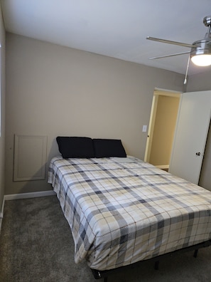 Ein Schlafzimmer mit einem Bett, einem Deckenventilator, einer Tür und einem Wandhoeschrank.