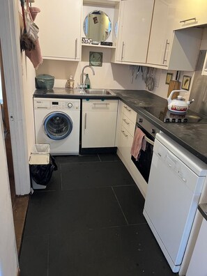 A compact kitchen with a washing machine, dishwasher, and a stove. - Cosy Garden flat in central Bristol, pet friendly (Bristol)