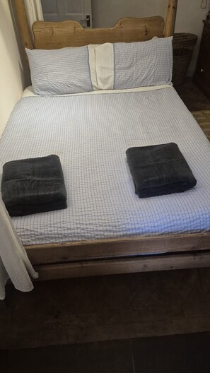 A bed with a wooden headboard, two pillows, and two folded towels. - Cosy Garden flat in central Bristol, pet friendly (Bristol)