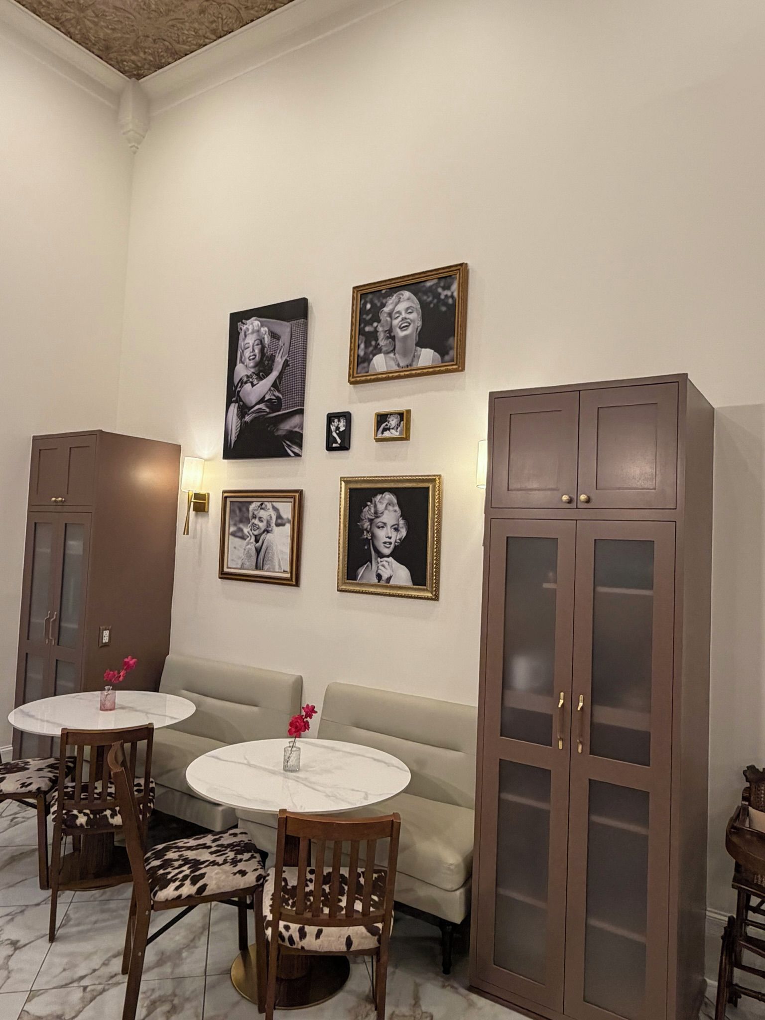 Een kamer met twee ronde tafels, een bank en een kast.