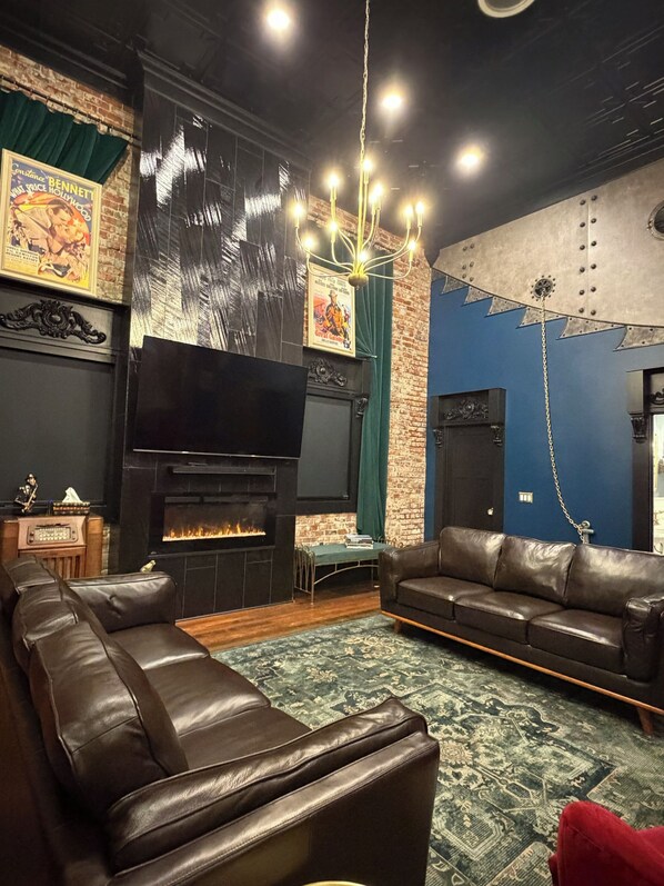 A living room with a fireplace, leather sofas, a television, and a patterned rug.