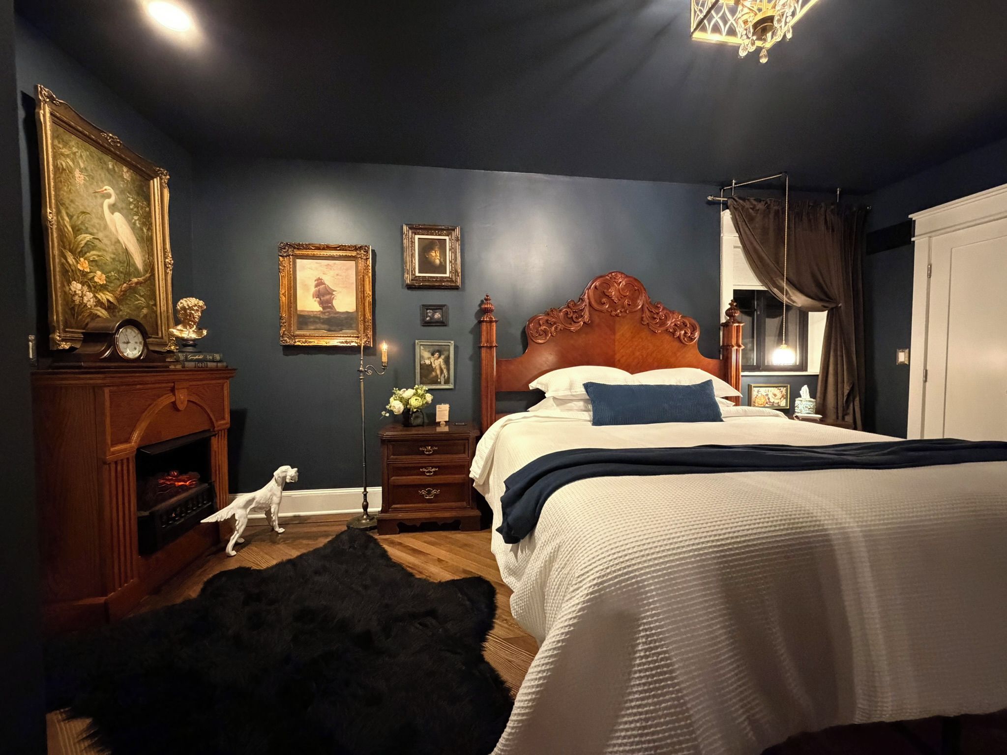 Een slaapkamer met een groot bed, een dressoir, een nachtkastje, een lamp en een schilderij aan de muur.