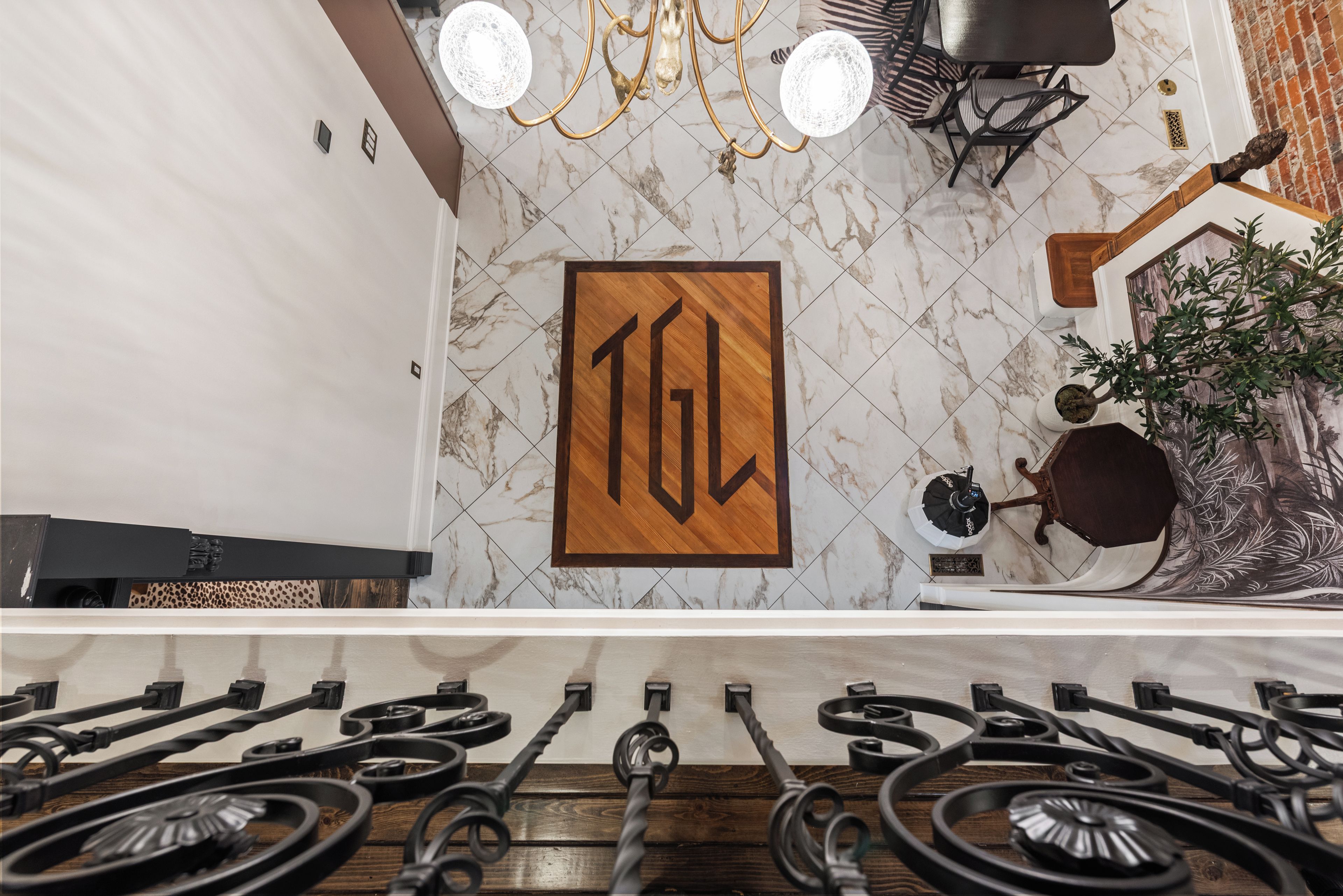 A kitchen with a marble backsplash, a wooden sign with the letters 'TGL', and a modern chandelier.