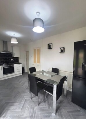 A modern kitchen with a dining table, chairs, and a refrigerator. - Halton Home Wi-Fi ideal for contractors WA7 (Weston Point)