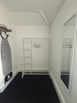 A walk-in closet with a metal hanger rack, a hanging iron, and a large mirror. - Halton Home Wi-Fi ideal for contractors WA7 (Weston Point)