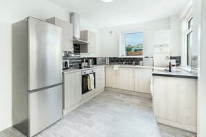A modern kitchen with stainless steel appliances, a microwave, and a window with a view. - Contractor • 3 Bed Home • Street Parking • Wi-Fi (Halton)