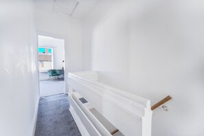 A hallway with a white wall, a carpeted floor, and a door leading to another room. - Contractor • 3 Bed Home • Street Parking • Wi-Fi (Halton)
