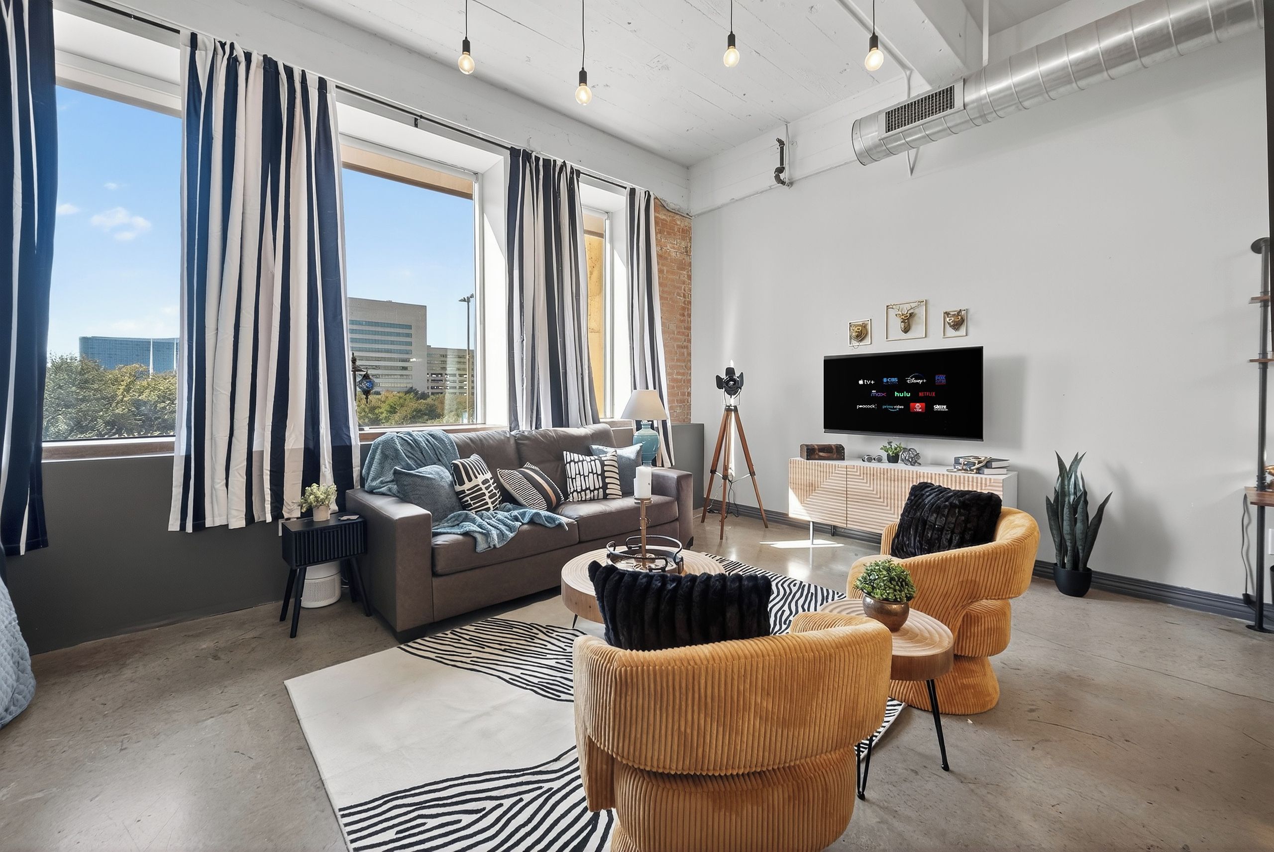A modern living room with a sofa, armchairs, a coffee table, and a TV.