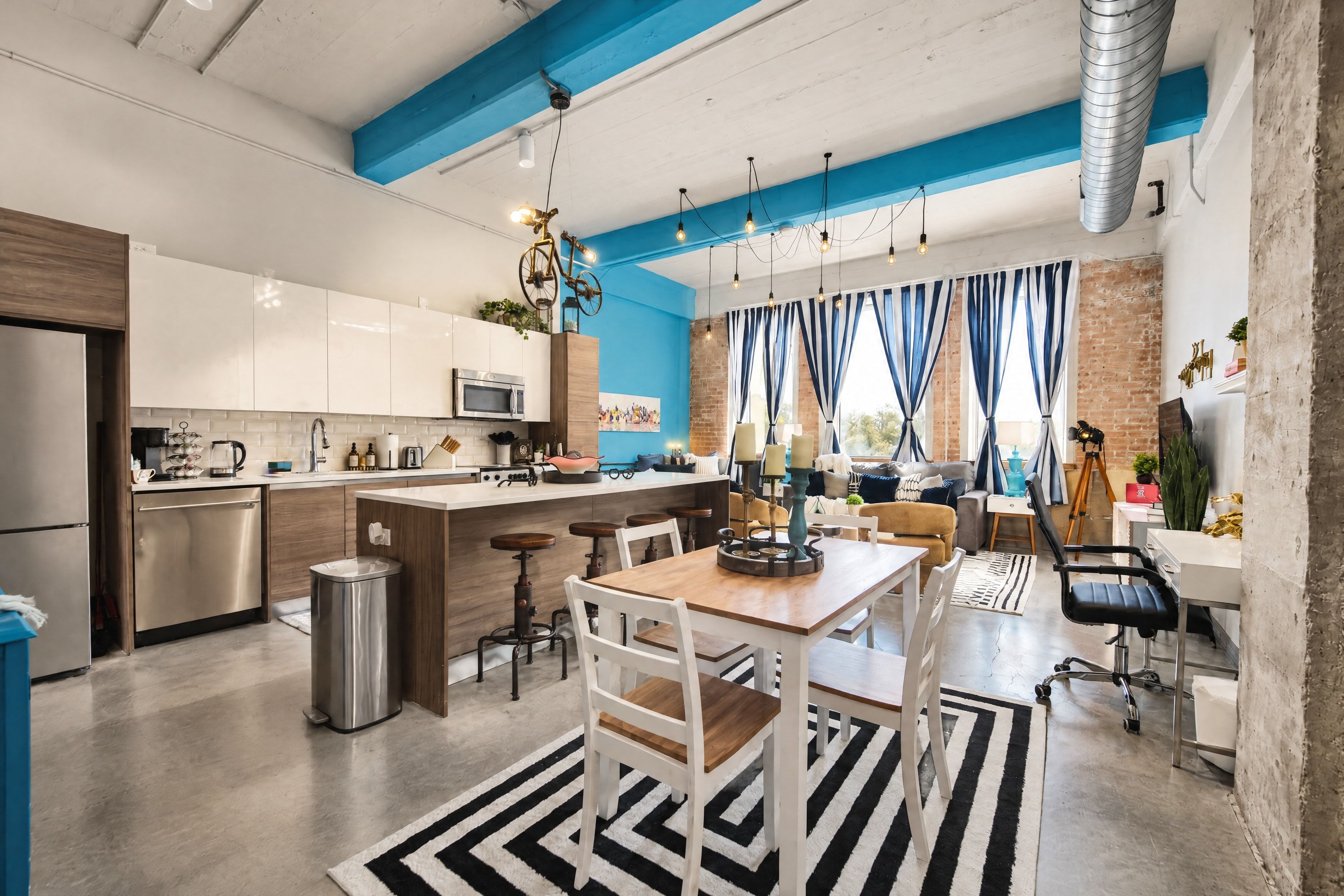 A modern kitchen with a central island, bar stools, and a dining area with a table and chairs.