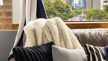 A city view from a window with a view of a tower and flags, a sofa with various cushions, and a curtain.
