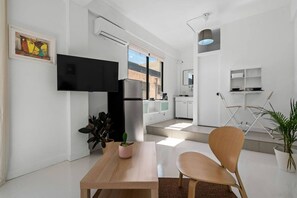 A modern living room with a flat-screen TV, a dining table with chairs, a kitchen area, and a large window. - San Rafael Apt 5 | Your 1BR Comfort Zone @San Juan (San Juan de Puerto Rico)