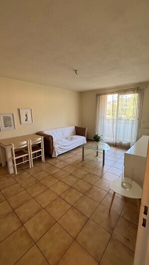 A living room with a sofa, a glass coffee table, a dining table with chairs, and a window with curtains. - Cozy apartment with a view of the Paillon garden (Nice)
