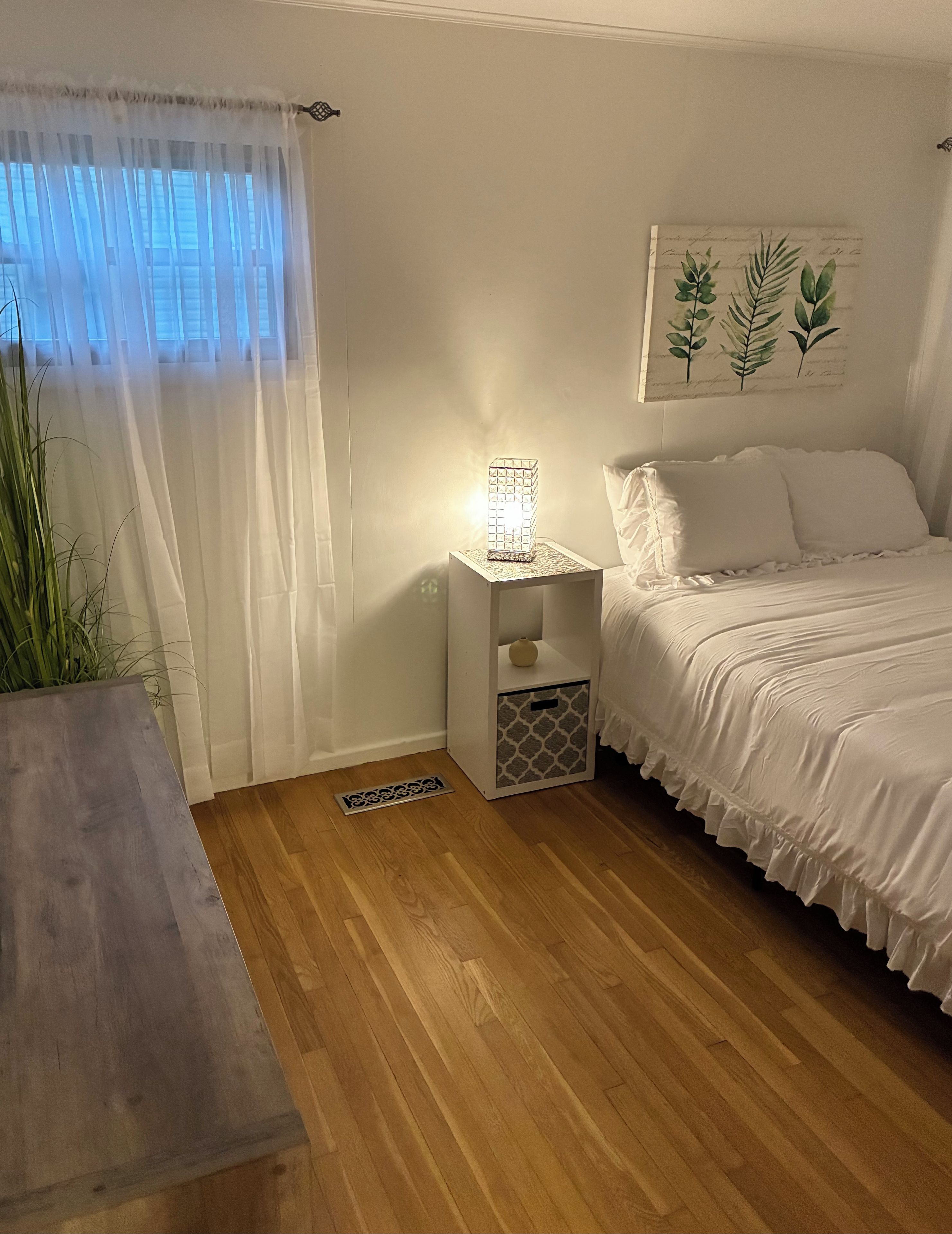 Ein Schlafzimmer mit einem Bett, einem Nachttisch und einem Beistelltisch mit Lampe.
