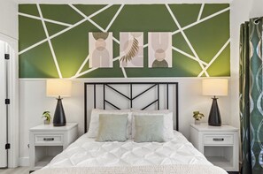 Una cama con cabecera geométrica, dos mesitas de noche con lámparas y una obra de arte en la pared.