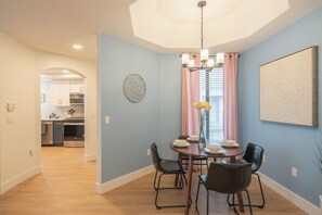 A dining area with a round table, black chairs, and a chandelier. There is a kitchen visible in the background. - Heated Pool | Walk to Westin Kierland - Park-W/D (Scottsdale)