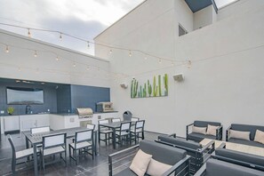 Eine Terrasse im Freien mit Grill, Sitzgelegenheit und Lichterkette.