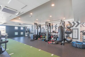Ein Fitnessraum mit unterschiedlichen Trainingsgeräten, einem Sandsack und einer Wand mit motivierenden Texten.