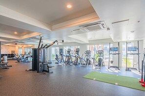 A spacious gym with various cardio machines, a weight training area, and large windows offering views of the outdoors. - Heated Pool | Workspace | Relaxing Workcation (Phoenix)