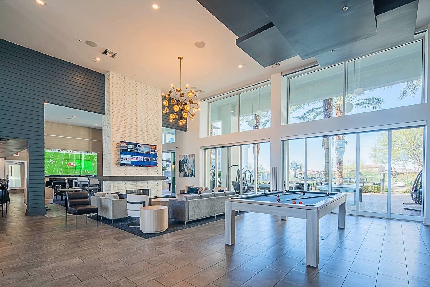 Un espacio interior amplio con mesa de billar, asientos cómodos, una gran pantalla de televisión y ventanas grandes que ofrecen vistas al exterior.
