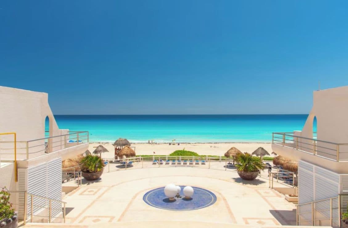 A resort with a pool area, beach view, and thatched umbrellas.