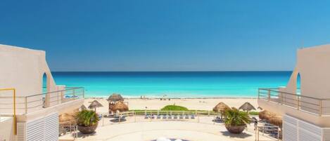 A resort with a pool area, beach view, and thatched umbrellas.