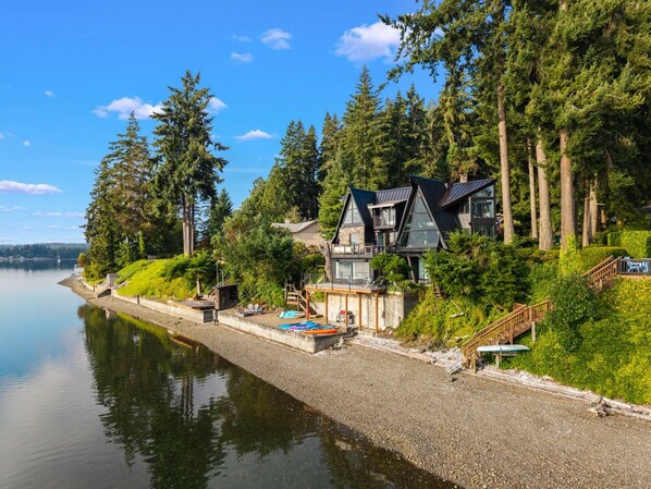 Una propiedad frente al lago con una casa, muelle y bosque circundante.